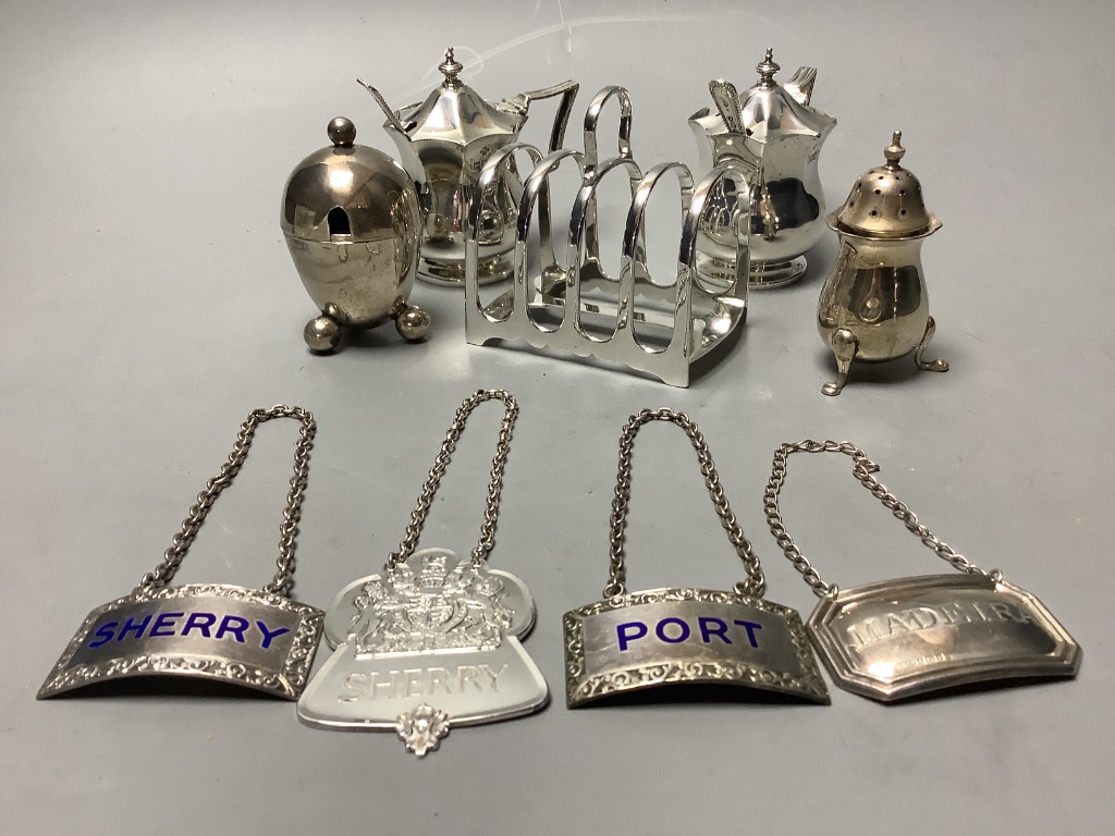 A pair of octagonal silver mustard pots and spoons, an egg-shaped salt, a baluster pepper, a small toast rack and four silver wine labels, approximately 13.5oz